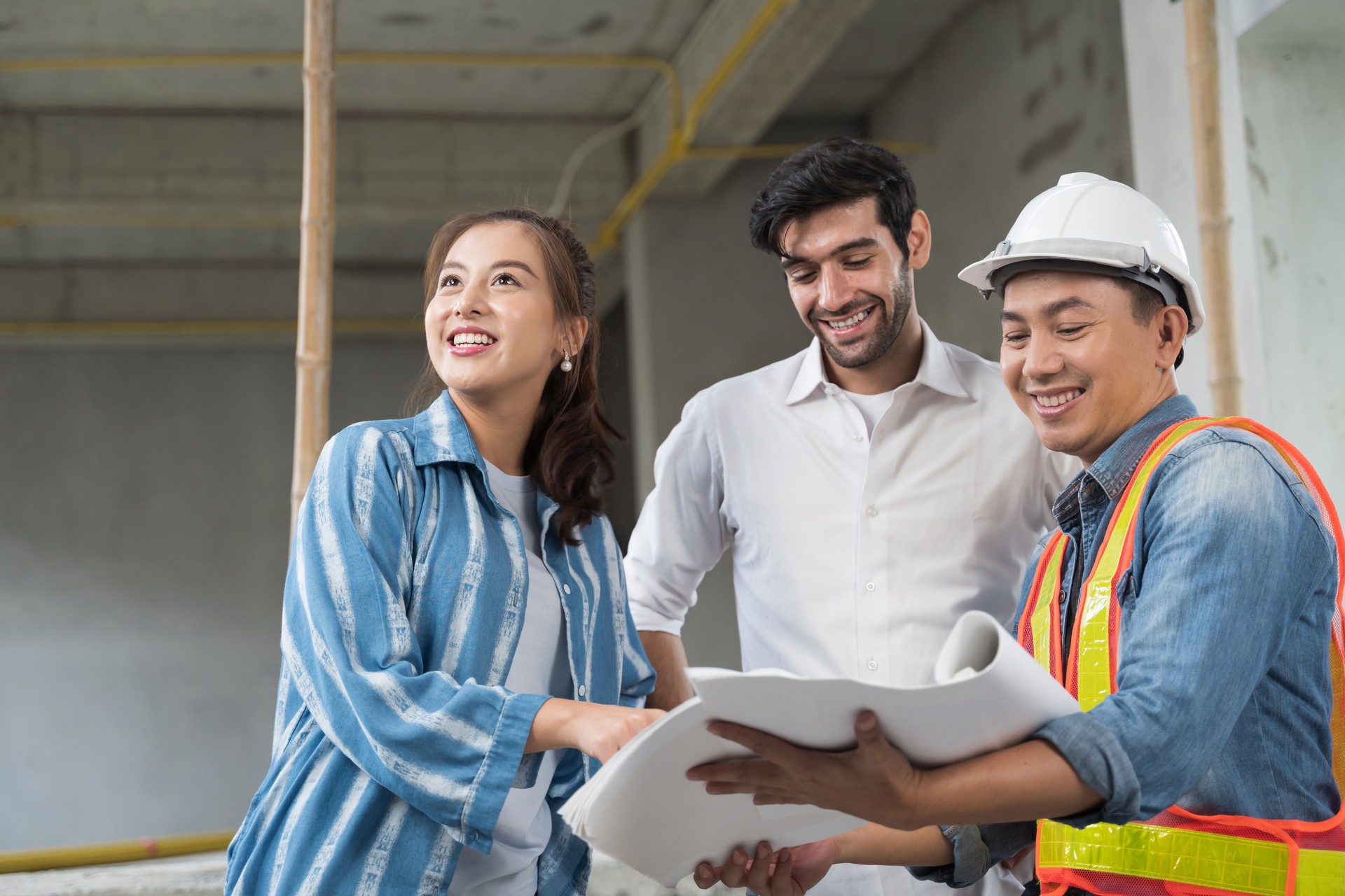 Asian couple checks the work of a contractor building a house for them.