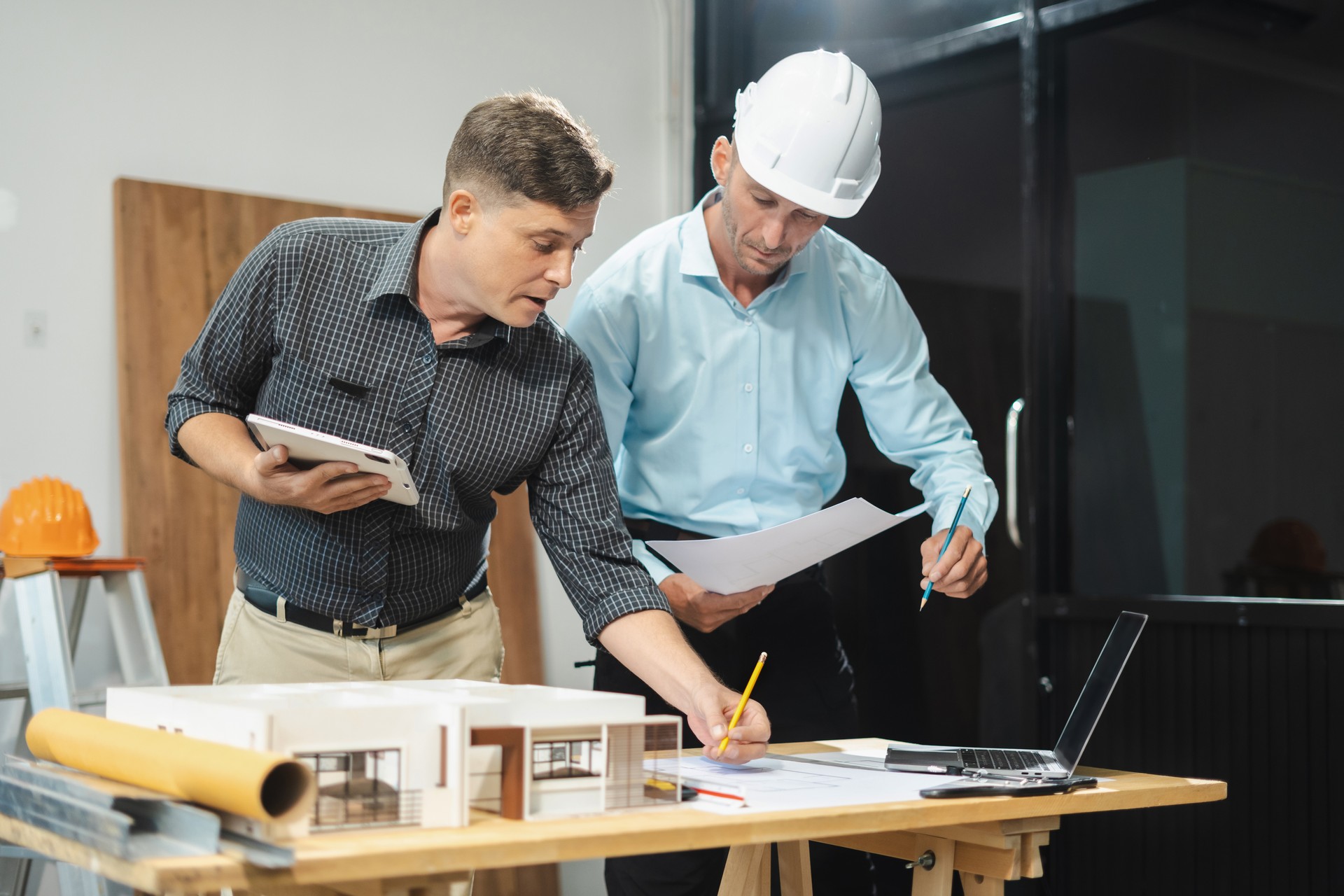 Architect caucasian man working, blueprint meeting for project working with partner on model building at company office.